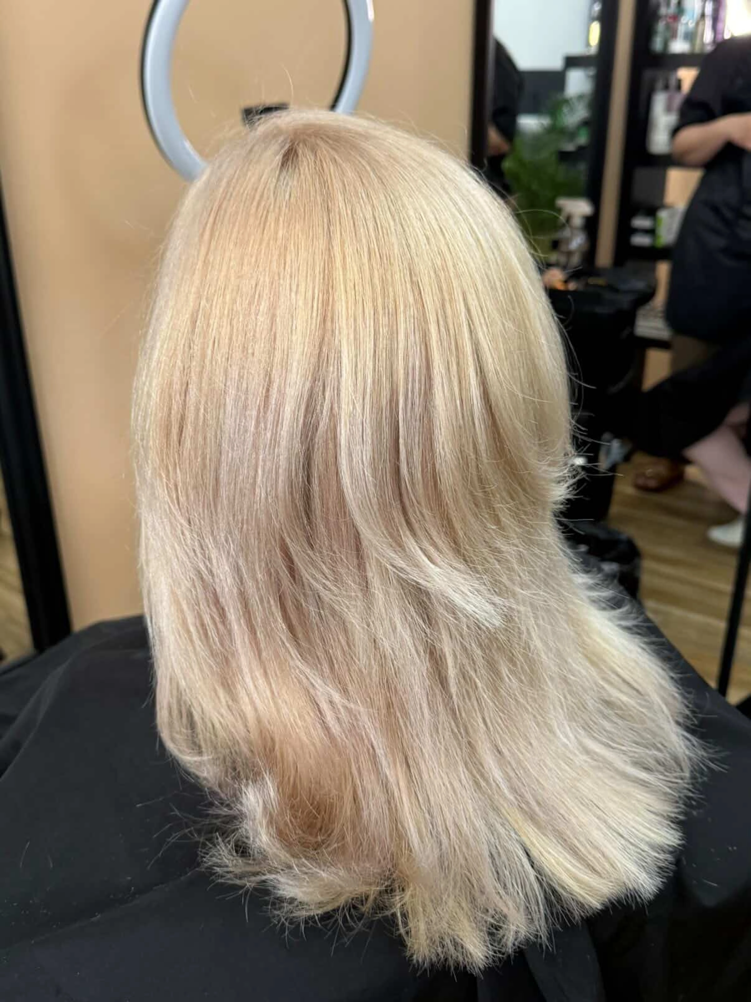 Vrstvené blond vlasy zobrazené zezadu.