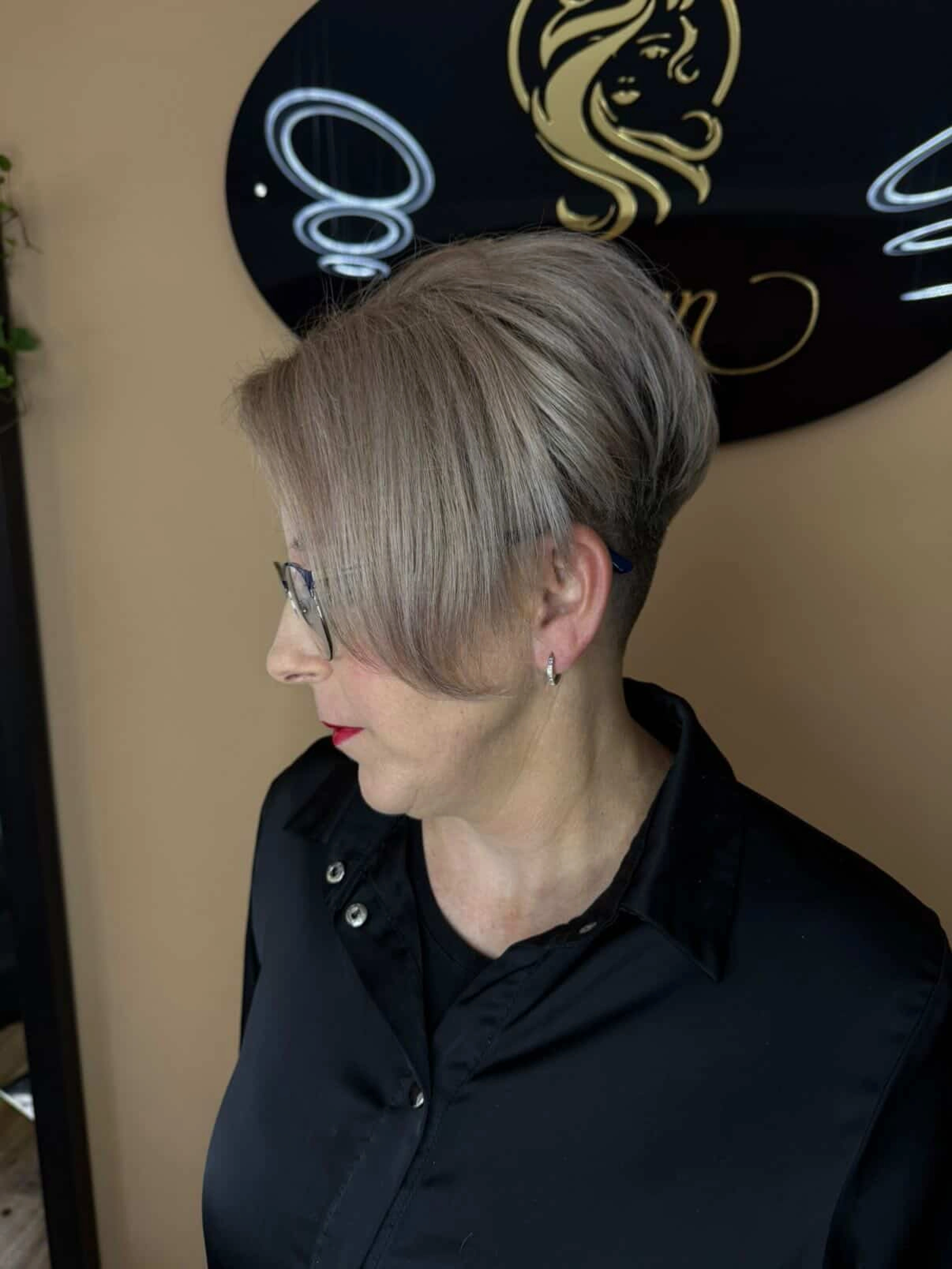 Krátký popelavě blond střih s podholením u ženy.