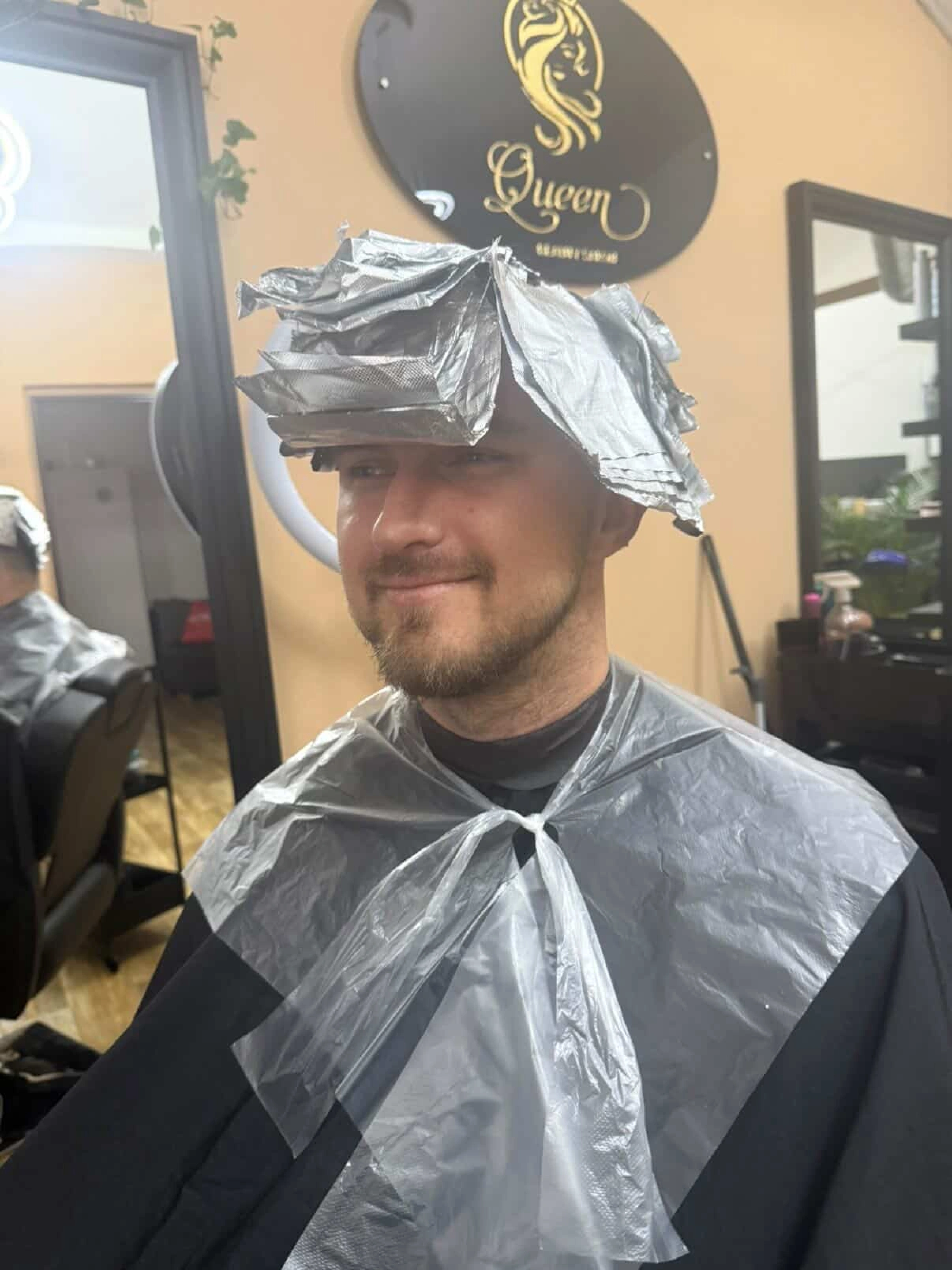 Muž s kadeřnickými alobaly na vlasech během barvení.