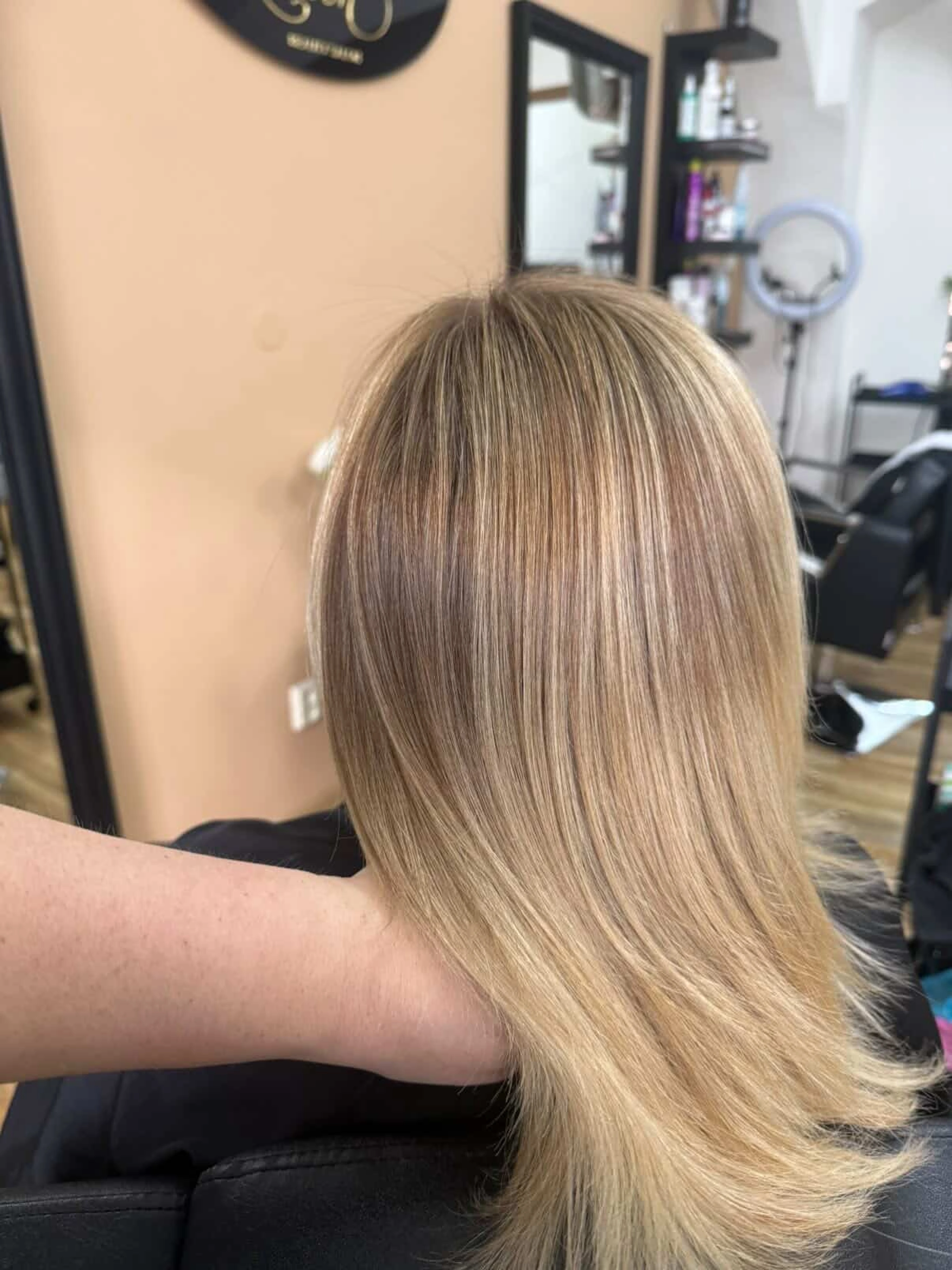 Vyhlazené blond vlasy s jemným melírem zobrazené zezadu.